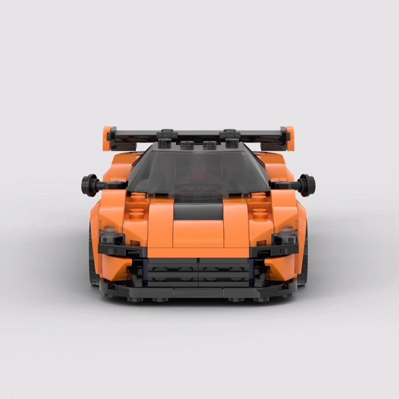 Front view of an orange toy sports car model with black accents and rear spoiler on gray background
