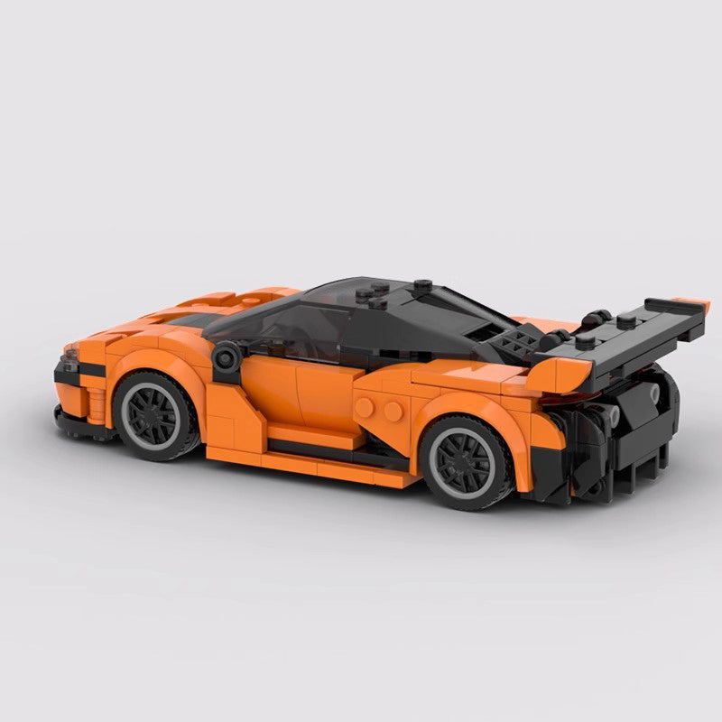 Orange and black LEGO sportscar model with rear spoiler, sleek design, and black wheels on white background