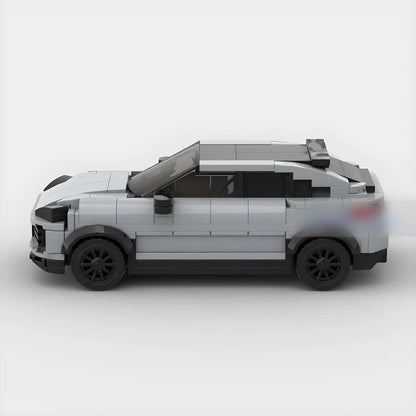 Side view of gray LEGO model car with black wheels and a rear spoiler on white background