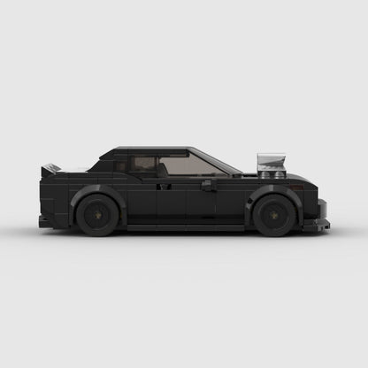 Black Lego muscle car model with hood scoop, rear spoiler, and detailed wheels on gray background